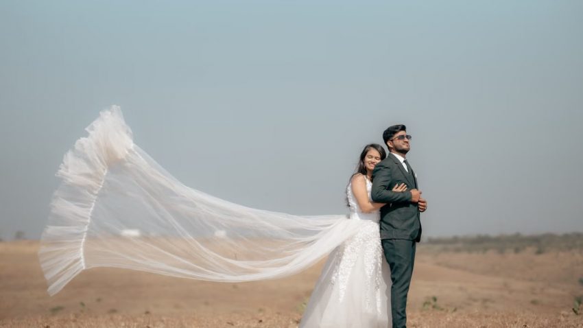 Elegant couple in outdoor pre-wedding photoshoot with flowing veil.